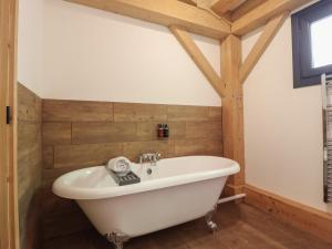 a white bath tub in a bathroom with wooden walls at Lady Bagots Cabin in Ruthin +28 photos