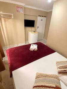 a bedroom with two white slippers on a bed at Caminho do Mar Hotel in Guarujá
