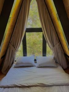 a bed in a room with a large window at Forest Whisper Lux - A-frame cabin with private hot tub in Kovačka Dolina