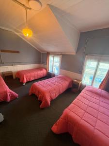 three beds in a room with red sheets at Hostal Papo in Osorno