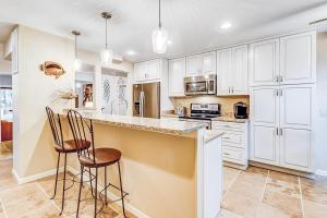 a kitchen with white cabinets and two bar stools at Beachwalk 124 in Hilton Head Island