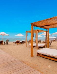 a beach with beds and umbrellas on the sand at Posada Las Rosas Inn in Quizandal +6 photos