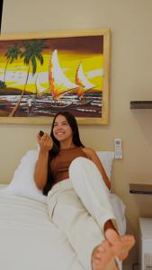 a woman laying on a bed talking on a phone at Pousada La Belle in Maragogi