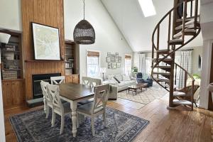 a living room with a wooden table and a spiral staircase at Firefly Cottage in Edisto Beach