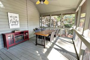 a screened in porch with a wooden table and chairs at Firefly Cottage in Edisto Beach