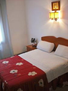 Schlafzimmer mit einem Bett mit einer roten und weißen Decke in der Unterkunft Hostal Cassa in Cassà de la Selva