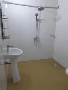 a white bathroom with a sink and a shower at Kolia Hgtel in Yamoussoukro