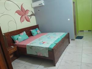 a small bed in a room with a flower on the wall at Kolia Hgtel in Yamoussoukro