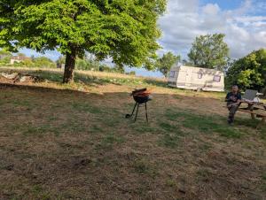 a woman sitting next to a grill in a field at Le soleil se lève in Virac