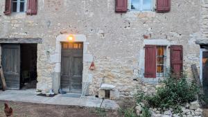 a stone building with two doors and a chicken outside at Le soleil se lève in Virac