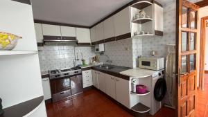 a small kitchen with white cabinets and a microwave at La Casa Azul en Ortigueira in Santa Marta de Ortigueira