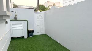 a white fence with a white door and green grass at Stylish 2BR Escape Near Muscat City Centre in Mawāliḩ