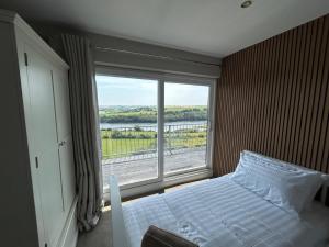 a bedroom with a bed and a large window at The Waterfront House in Kinsale, hosted by Exquisite Holiday Homes in Dunderrow