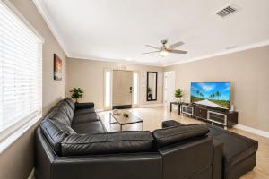 a living room with a leather couch and a flat screen tv at Walk to Hollywood Beach Luxury 4BR Villa in Hollywood