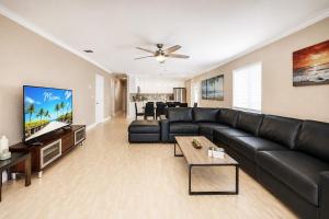a living room with a black leather couch and a flat screen tv at Walk to Hollywood Beach Luxury 4BR Villa in Hollywood