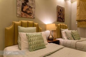 a bedroom with two beds with green and white pillows at Chalet A4 Mirbat in Mirbāţ