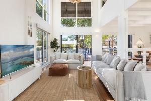 a living room with white furniture and a large tv at Maisie's in Tathra