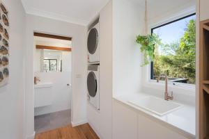 a white kitchen with a sink and a window at Maisie's in Tathra +36 photos