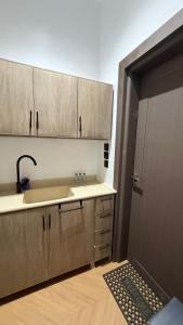 a kitchen with wooden cabinets and a sink and a door at استديو فندقي دخول ذكي عائلي مريح in Al Ahsa +9 photos