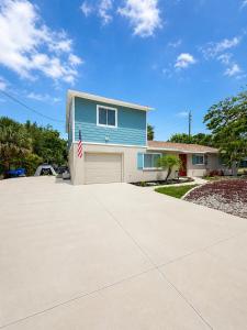 a blue house with a garage and an american flag at Bradenton Oasis Private Backyard and Firepit in Bradenton