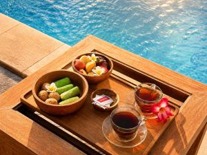 a tray with two bowls of fruit and a glass of wine at SūKha Amed in Culik