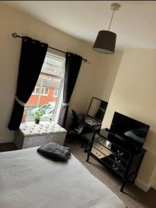 ein Schlafzimmer mit Bett, Fernseher und Fenster in der Unterkunft Bentley View in Crewe