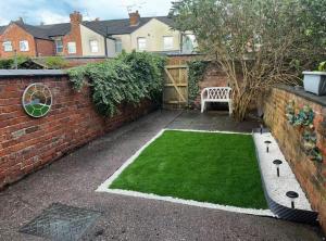 ein kleiner Garten mit einer Bank neben einer Backsteinmauer in der Unterkunft Bentley View in Crewe
