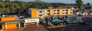a large building with cars parked in a parking lot at Hotel Palmeiras in Laranjeiras do Sul