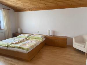 a bedroom with a bed and a white chair at Ferienhaus Wolfurt in Wolfurt