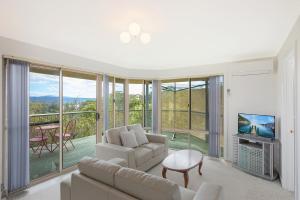 a living room with a couch and a tv and a balcony at Holiday on Pacific in Tathra