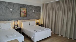 a hotel room with two beds and a window at Hotel Palmeiras in Laranjeiras do Sul +32 photos