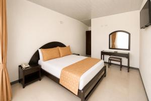 a bedroom with a bed and a table and a mirror at Alborada Hotel Melgar in Melgar +16 photos