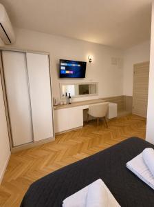 a bedroom with a bed and a desk with a television at Apartments & Rooms Prižmić in Podstrana
