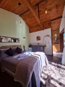 a bedroom with a large bed in a room with wooden ceilings at Chalés Refúgio no Campo in Santo Antônio do Pinhal