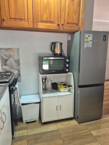 a kitchen with a refrigerator and a microwave at Casa bosque arenal in Pucón