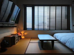 a bedroom with a bed and a table and windows at Sōlis Inn 宿里旅行舍 in Hualien City