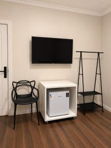 a room with a tv on a wall with a chair at ParaHouse in Joinville