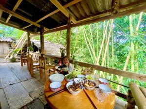 a woman sitting at a table with food on it at Red Dao Homestay and Entire bungalow in Tả Van