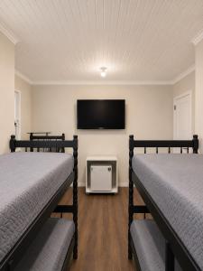 two beds in a room with a flat screen tv at ParaHouse in Joinville