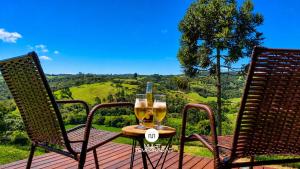 two chairs and a table with two glasses of wine at Cabana Bad Wolf - Rancho Queimado - SC in Rancho Queimado