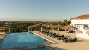 ein Swimmingpool mit Liegestühlen und Sonnenschirmen in der Unterkunft Monte do Alento - Castro da Cola in Alcaria