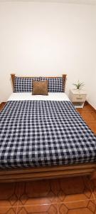 a bed with a blue and white checkered mattress at Morada Living Bello HomeStay in Bello