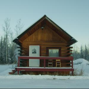 a log cabin with a bench in the snow at Caribou Cabin -Rustic Cabin with Sauna in Delta Junction