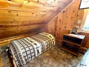 a bedroom with a bed and a wooden wall at Caribou Cabin -Rustic Cabin with Sauna in Delta Junction