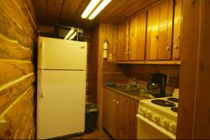 a kitchen with a white refrigerator and a stove at Caribou Cabin -Rustic Cabin with Sauna in Delta Junction +6 photos