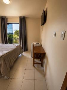 a bedroom with a bed and a desk with a television at hotel Maanaim in Candói