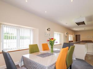 a dining room with a table with chairs and a vase of flowers at Millmoss Cottage in Turriff