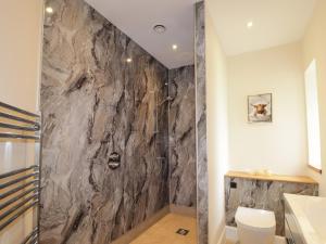 a bathroom with a shower with a stone wall at Millmoss Cottage in Turriff +19 photos