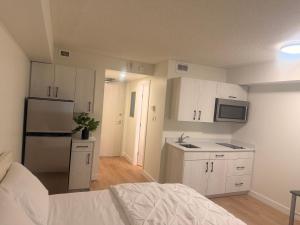 a small kitchen with white cabinets and a refrigerator at Urban Nest in Edmonton