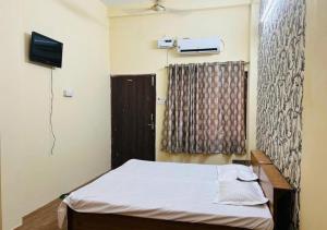 a bedroom with a bed and a television and a window at The Kishan's Nest in Mathura